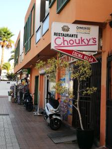 a store with a scooter parked outside of a building at PLAYA LAS VISTAS LOFT in Los Cristianos