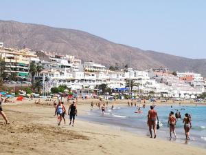 a group of people walking on a beach at PLAYA LAS VISTAS LOFT in Los Cristianos
