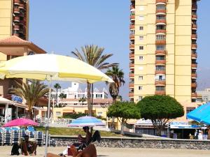 a group of people sitting under umbrellas at a beach at PLAYA LAS VISTAS LOFT in Los Cristianos