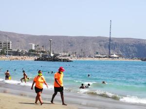 two people in yellow shirts walking on the beach at PLAYA LAS VISTAS LOFT in Los Cristianos