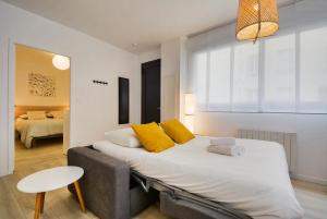 Un dormitorio con una cama grande con almohadas amarillas. en L'indépendant de la rue du Tapis Vert - Appt Nancy, en Nancy