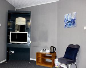 ブラックプールにあるHenson Hotel Pleasure Beachの椅子、テレビ、テーブルが備わる客室です。
