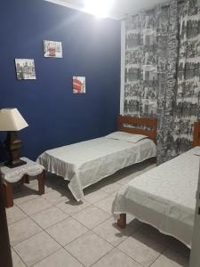Zimmer mit 2 Betten, einem Tisch und einer Lampe in der Unterkunft PITANGUEIRAS BEACH in Guarujá