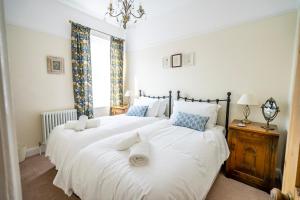 1 dormitorio con 2 camas con sábanas blancas y ventana en Victoria Cottage, en York