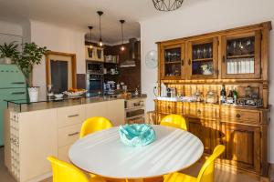 a kitchen with a white table and yellow chairs at D09 - Porto de Mós Luxury Villa in Lagos