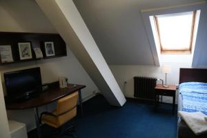 a room with a bed and a desk and a window at Pension & Restaurace Na Rychtě in Prague