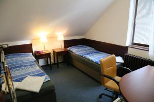 a small room with two beds and a table and chairs at Pension & Restaurace Na Rychtě in Prague