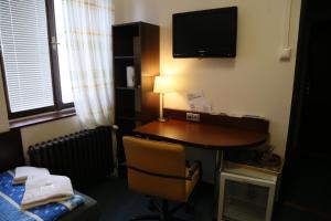 Habitación de hotel con escritorio y TV en la pared en Pension & Restaurace Na Rychtě, en Praga
