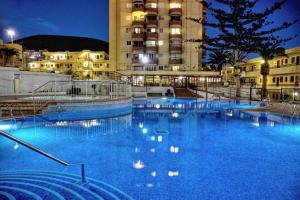 a large pool of blue water in front of a building at PLAYA LAS VISTAS LOFT in Los Cristianos