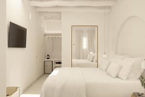 een witte slaapkamer met een groot wit bed en een spiegel bij LLONGA'S 7th in Ciutadella
