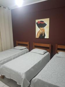 ein Zimmer mit 2 Betten und ein Bild einer Frau in der Unterkunft PITANGUEIRAS BEACH in Guarujá