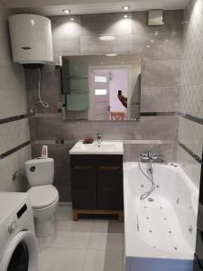 a bathroom with a tub and a toilet and a sink at Apartament Zielony in Włodawa