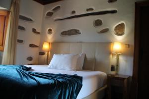 1 dormitorio con 1 cama con rocas en la pared en Refúgios do Pinhal, en Oleiros