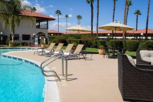 uma piscina com cadeiras e guarda-sóis num resort em Hotel Mission De Oro em Santa Nella