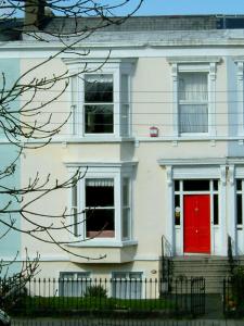 a white house with a red door at Claremont House in Dun Laoghaire