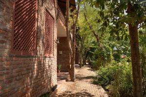 a brick building with a brick walkway next to a tree at Fateh's Retreat, Homestay in Sawāi Mādhopur