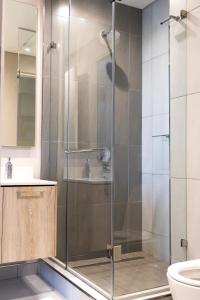 La salle de bains est pourvue d'une douche avec une porte en verre. dans l'établissement The Residence Luxury Studio - Menlyn Maine, à Pretoria
