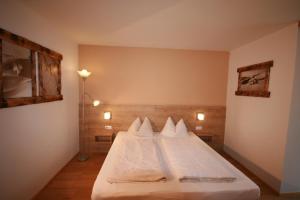 カプルーンにあるAppartements Domizilのベッドルーム1室(白いシーツと枕のベッド1台付)