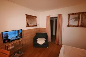 a living room with a television and a chair at Appartements Domizil in Kaprun