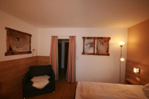 a bedroom with a bed and a chair and a window at Appartements Domizil in Kaprun