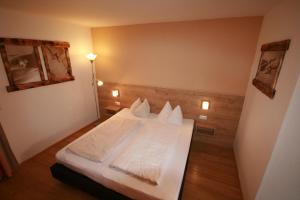 1 dormitorio con 1 cama con sábanas y almohadas blancas en Appartements Domizil, en Kaprun