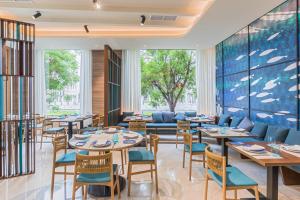 a restaurant with tables and chairs and a couch at Occidental Sevilla Viapol in Seville