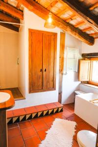 a bathroom with a wooden door and a tile floor at Masia Pou de la Vinya in Sitges