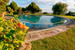 a swimming pool with a hose in the grass at Hotel Spartivento in Chia