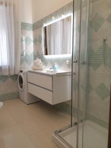 W łazience znajduje się prysznic, umywalka i pralka. w obiekcie Cottage al mare Martina w Lido di Venezia