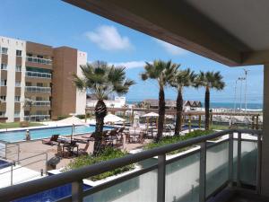 a balcony with palm trees and a swimming pool at VG Fun Beach Front Apartamentos in Fortaleza