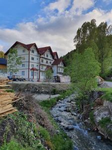 a large white building next to a river at Vila 4 Anotimpuri in Moieciu de Sus