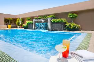 a swimming pool with a drink on a table next to it at Novotel Mexico City Santa Fe in Mexico City