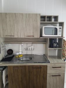 a small kitchen with a sink and a microwave at Apartamento Bombas in Bombinhas