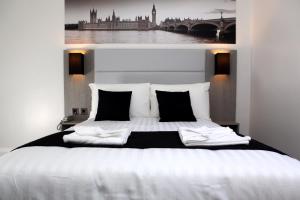 a bedroom with a large white bed with black pillows at The Omega Hotel in London