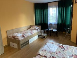 a bedroom with two beds and a table and a window at Vesi's Rooms in Plovdiv