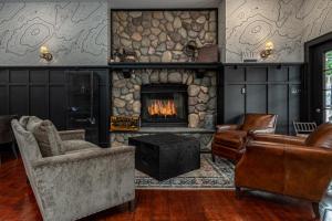 a living room with a stone fireplace and furniture at The Alpine Lodge in North Creek