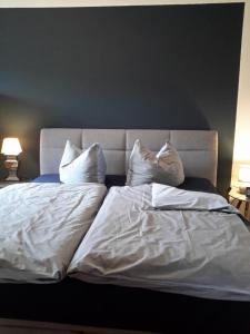 een groot bed met witte lakens en kussens bij Appartement Luthers Stübchen in Lutherstadt Wittenberg