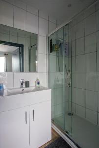 a bathroom with a sink and a glass shower at Beautiful river balcony cottage in heart of historic sandwich in Kent