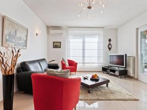 un soggiorno con divano nero e sedie rosse di Belvilla by OYO Varese Tre a Comerio