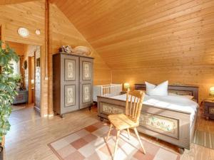 Chalet in Hinterrod Thuringia with sauna في Eisfeld: غرفة نوم بسرير وكرسي في غرفة