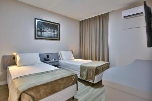 a hotel room with two beds and a tv at Vivendas Rio Claro by Atlantica in Rio Claro