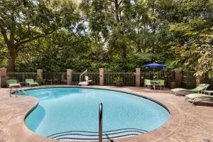 a swimming pool with chairs and a table and an umbrella at Holiday Inn Express Hotel & Suites Mount Pleasant - Charleston by IHG in Charleston