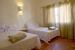 a hotel room with two beds and a window at Bungalows Las Arenas in San Patricio Melaque