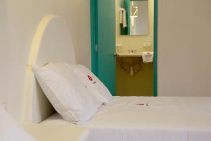 a white bed in a room with a mirror at Bungalows Las Arenas in San Patricio Melaque