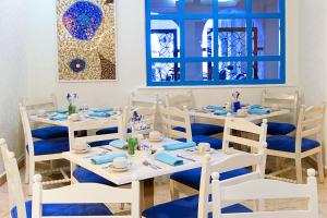 a dining room with white tables and blue chairs at GR Caribe Deluxe By Solaris All Inclusive in Cancún
