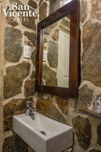 a bathroom with a sink and a mirror on a stone wall at Hotel Termales San Vicente in Santa Rosa de Cabal