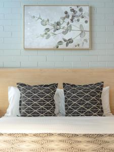 a bed with two pillows and a painting on the wall at Fitzroy Motor Inn in Grafton