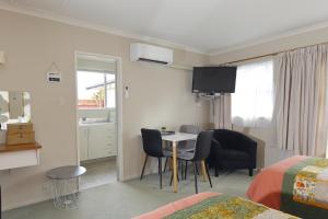 a room with a table and chairs and a bedroom at Aden Motel in Te Anau