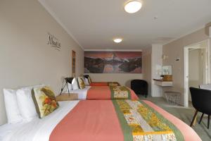 a hotel room with two beds and a desk at Aden Motel in Te Anau