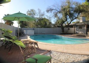 a swimming pool with a table and an umbrella at Tempe Escape with Heated Pool, Billiards & Firepit Fun in Tempe